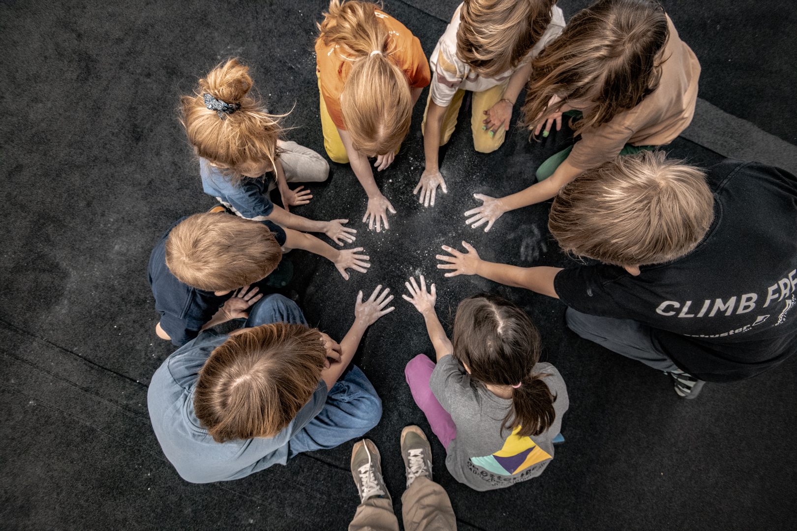 Eine Gruppe von Kindern hat Chalk an den Händen und macht Abdrücke auf die Bouldermatte